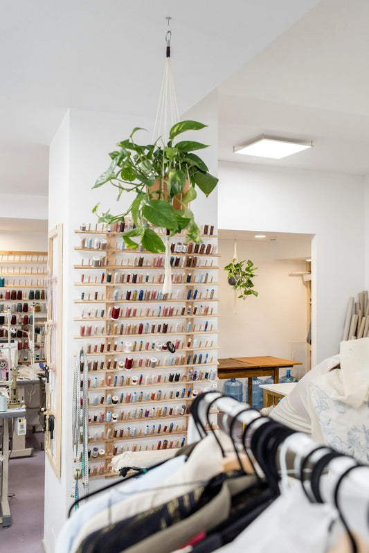 The inside of a garment tailor featuring a wall rack of thread spools