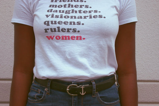 Woman Wearing White T-shirt and Blue Denim Bottoms. Shirt reads: friends. mothers. daughters. visionaries. queens. rulers. women.